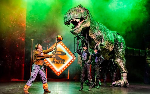 Stage performance of Dinosaur World Live with a large dinosaur puppet, Westend.