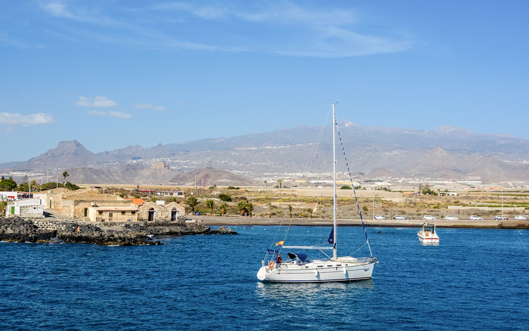 Sailboat on the water near Marina del Sur, Las Galletas, Tenerife, Spain with mountains in the background.