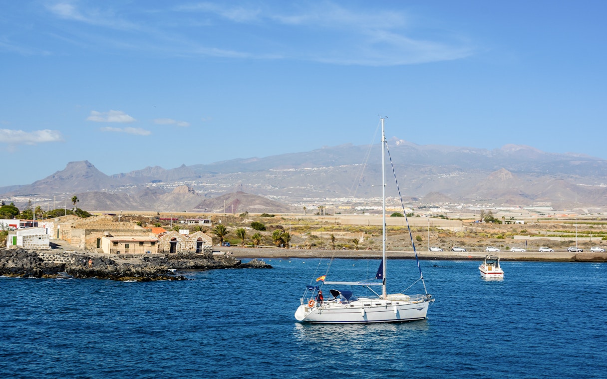 Sailboat on the water near Marina del Sur, Las Galletas, Tenerife, Spain with mountains in the background.