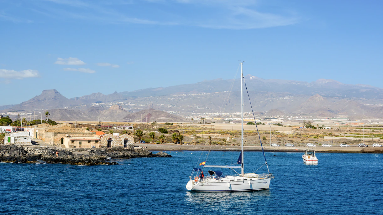 Sailboat on the water near Marina del Sur, Las Galletas, Tenerife, Spain with mountains in the background.