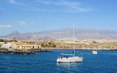 Sailboat on the water near Marina del Sur, Las Galletas, Tenerife, Spain with mountains in the background.