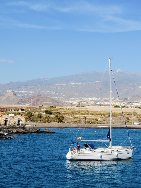 Sailboat on the water near Marina del Sur, Las Galletas, Tenerife, Spain with mountains in the background.