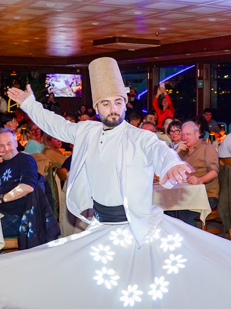 Whirling dervish performing on Bosphorus dinner cruise with live audience.