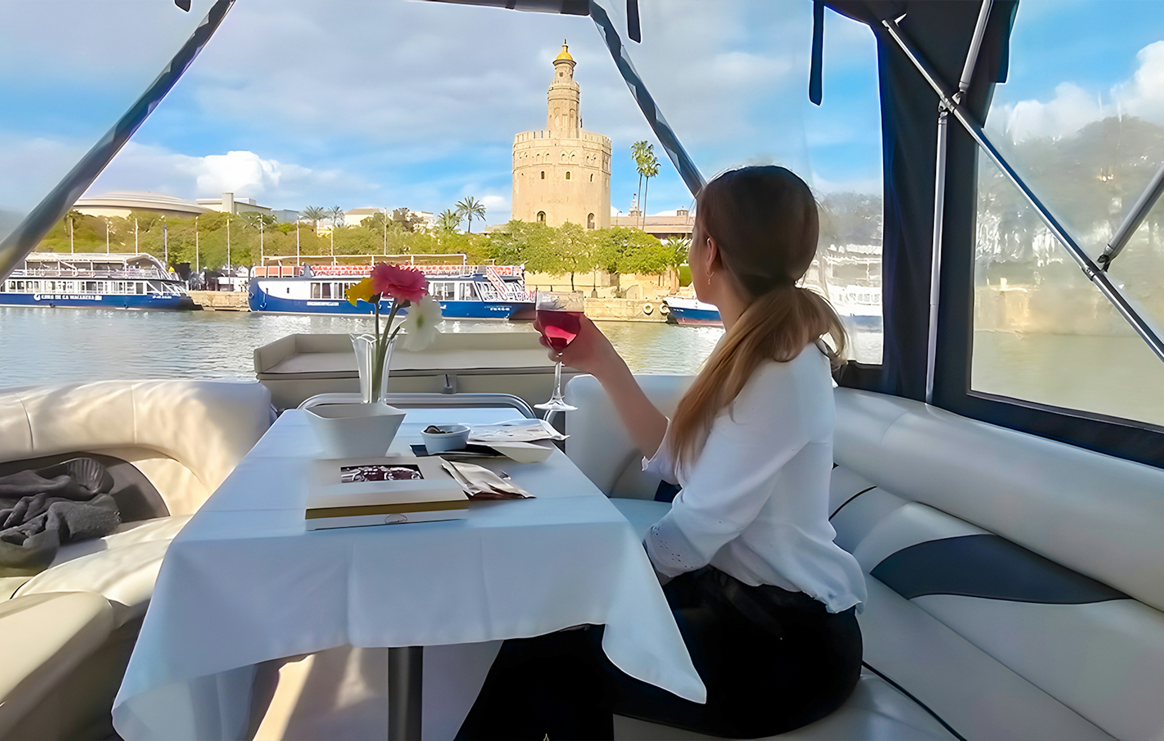 Tourist on Guadalquivir River Cruise enjoying view of Torre del Oro with tapas and drink.