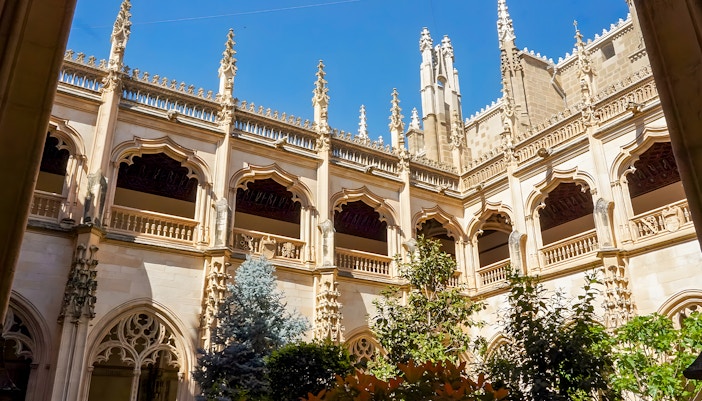 Courtyard view of Monastery of San Juan de los Reyes with Gothic arches and greenery.
