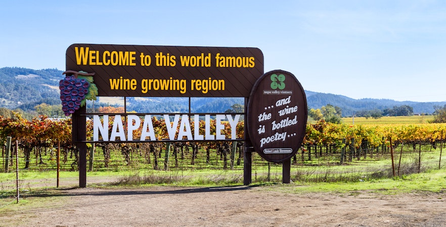 Napa Valley welcome sign with vineyards in the background.