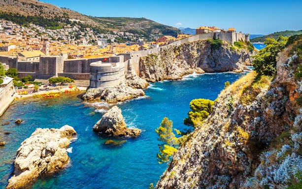 Dubrovnik old town walls overlooking the Adriatic Sea with rocky cliffs and historic architecture.