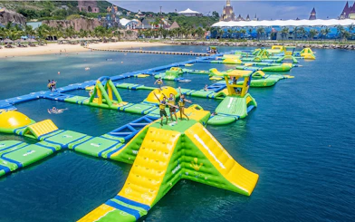 Floating water park with slides and obstacles at Splash Bay, featuring people enjoying activities.