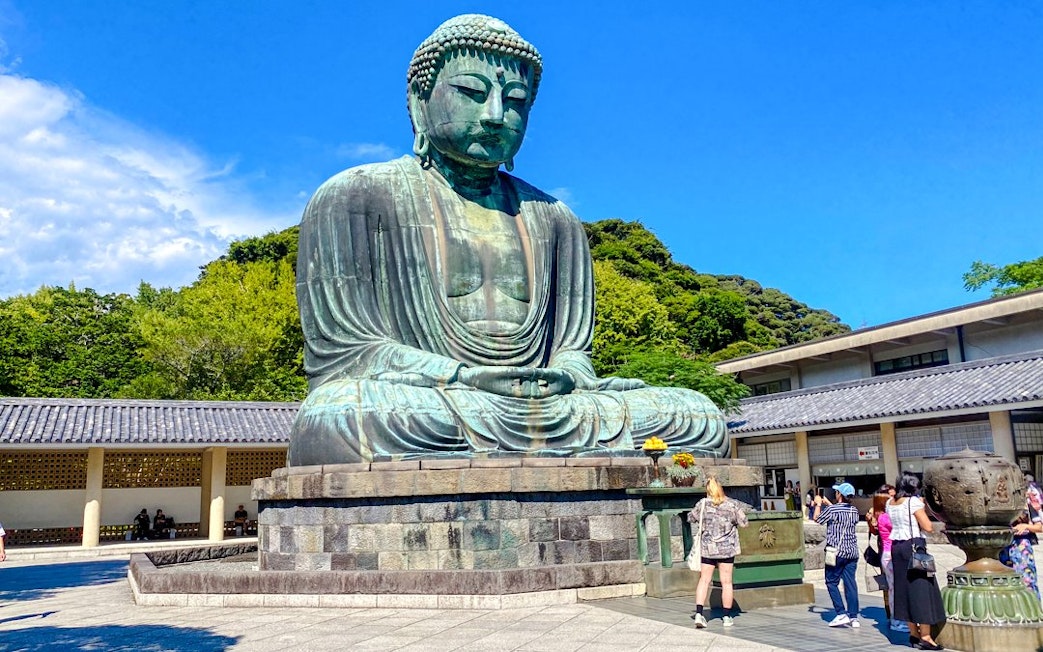Giant Buddha statue at Kamakura with tourists exploring the site.