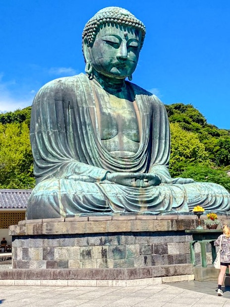 Giant Buddha statue at Kamakura with tourists exploring the site.