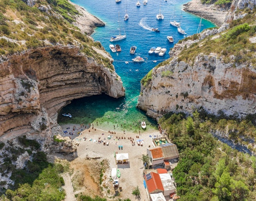 Aerial view of Stiniva Cove beach with boats and visitors on Vis Island, Croatia.