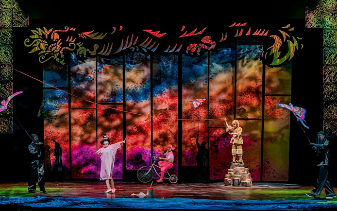 Performance of The Dragon Child with colorful backdrop and actors on stage, Sydney.