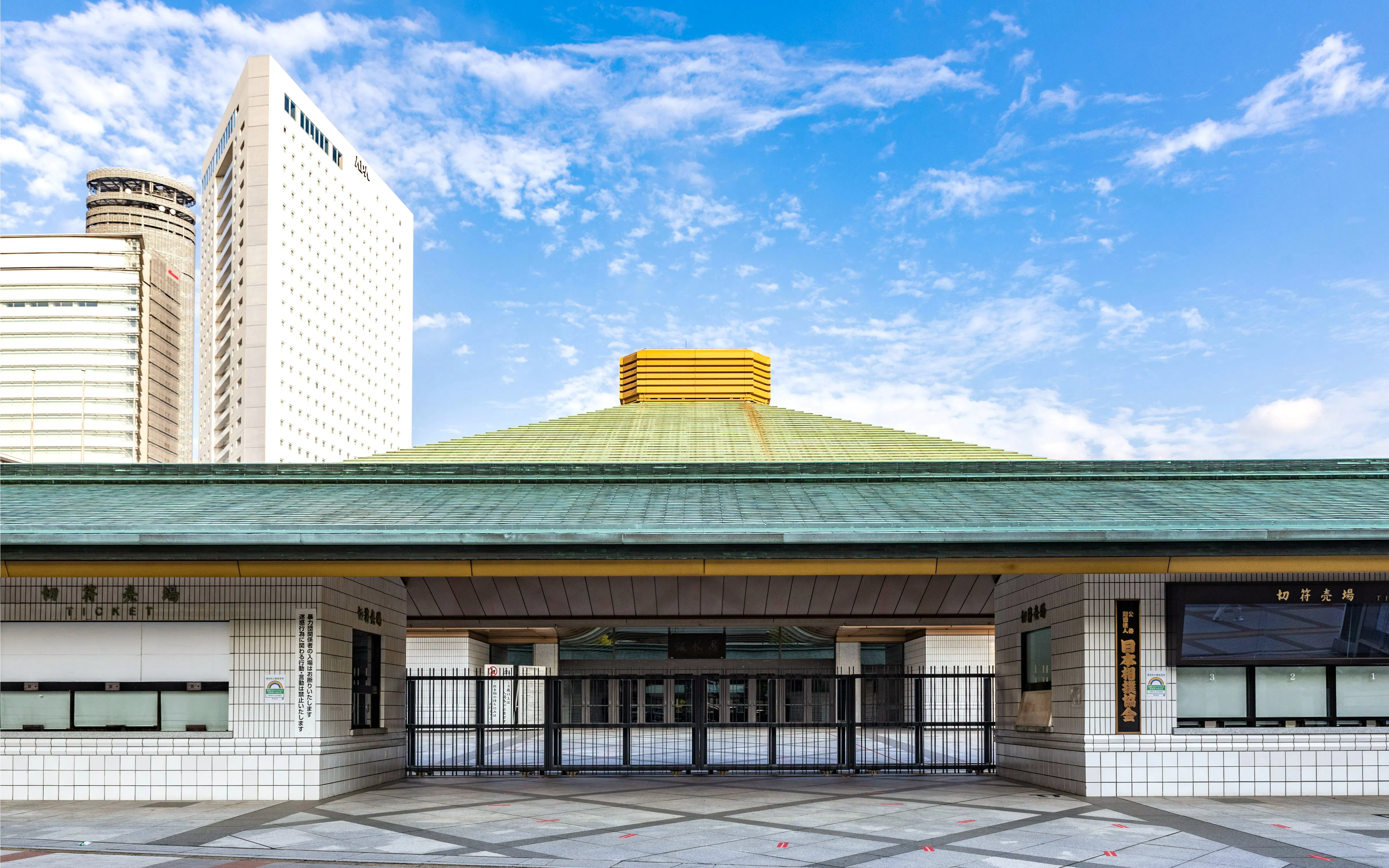 Ryogoku Kokugikan entrance in Yokoami, Sumida, Tokyo, Japan, with modern buildings in the background.