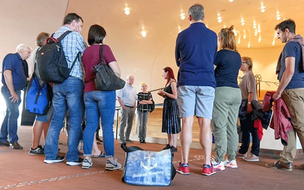 Group touring Hamburg Elbphilharmonie with guide, Störtebeker beer bag visible.
