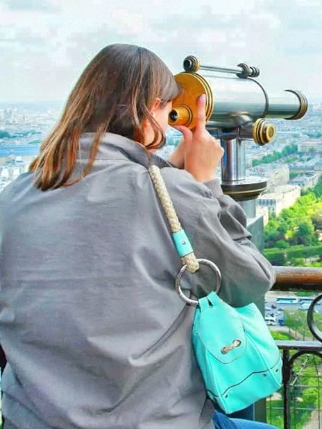 Tourist using telescope to view Trocadero from Eiffel Tower, Paris.