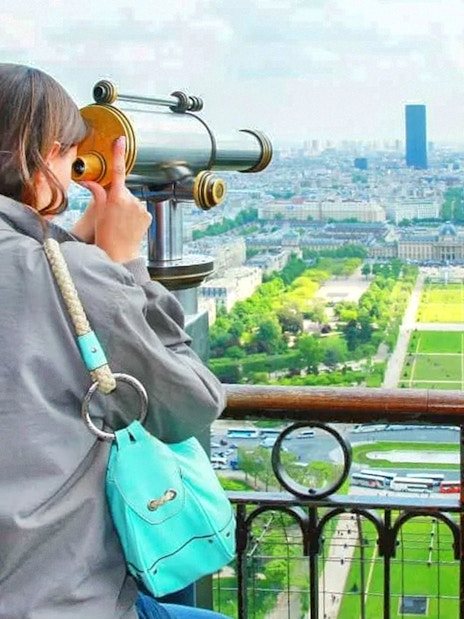 Tourist using telescope to view Trocadero from Eiffel Tower, Paris.