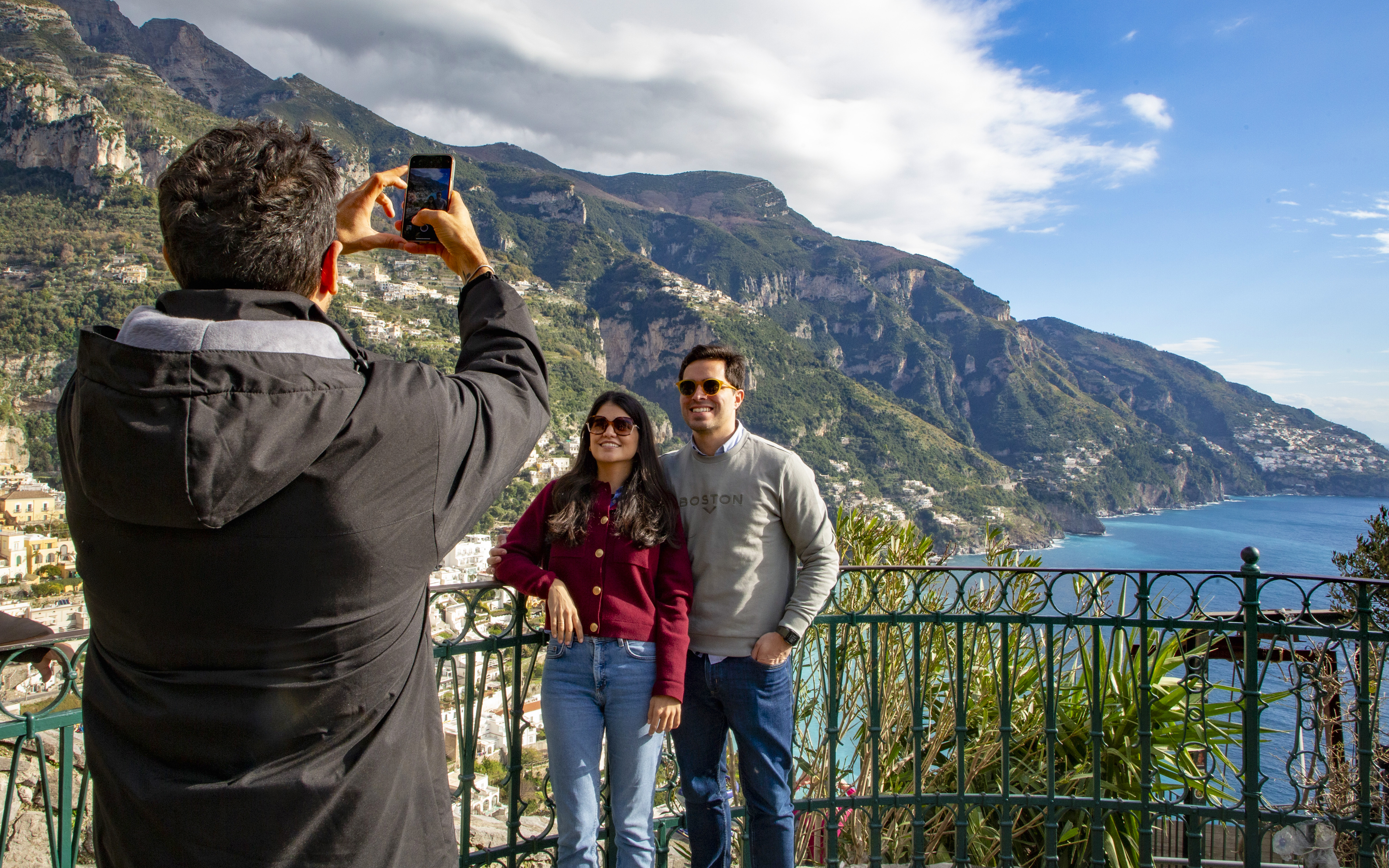 Tourists posing for a photo with scenic view of the Amalfi Coast in Positano, Italy.