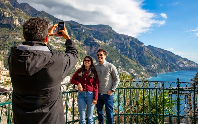 Tourists posing for a photo with scenic view of the Amalfi Coast in Positano, Italy.
