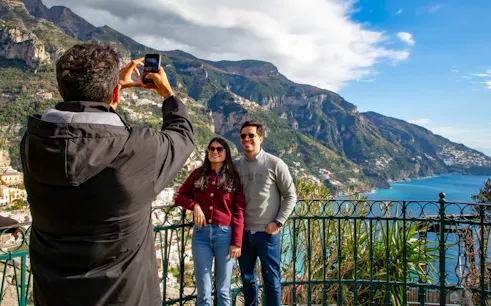 Tourists posing for a photo with scenic view of the Amalfi Coast in Positano, Italy.
