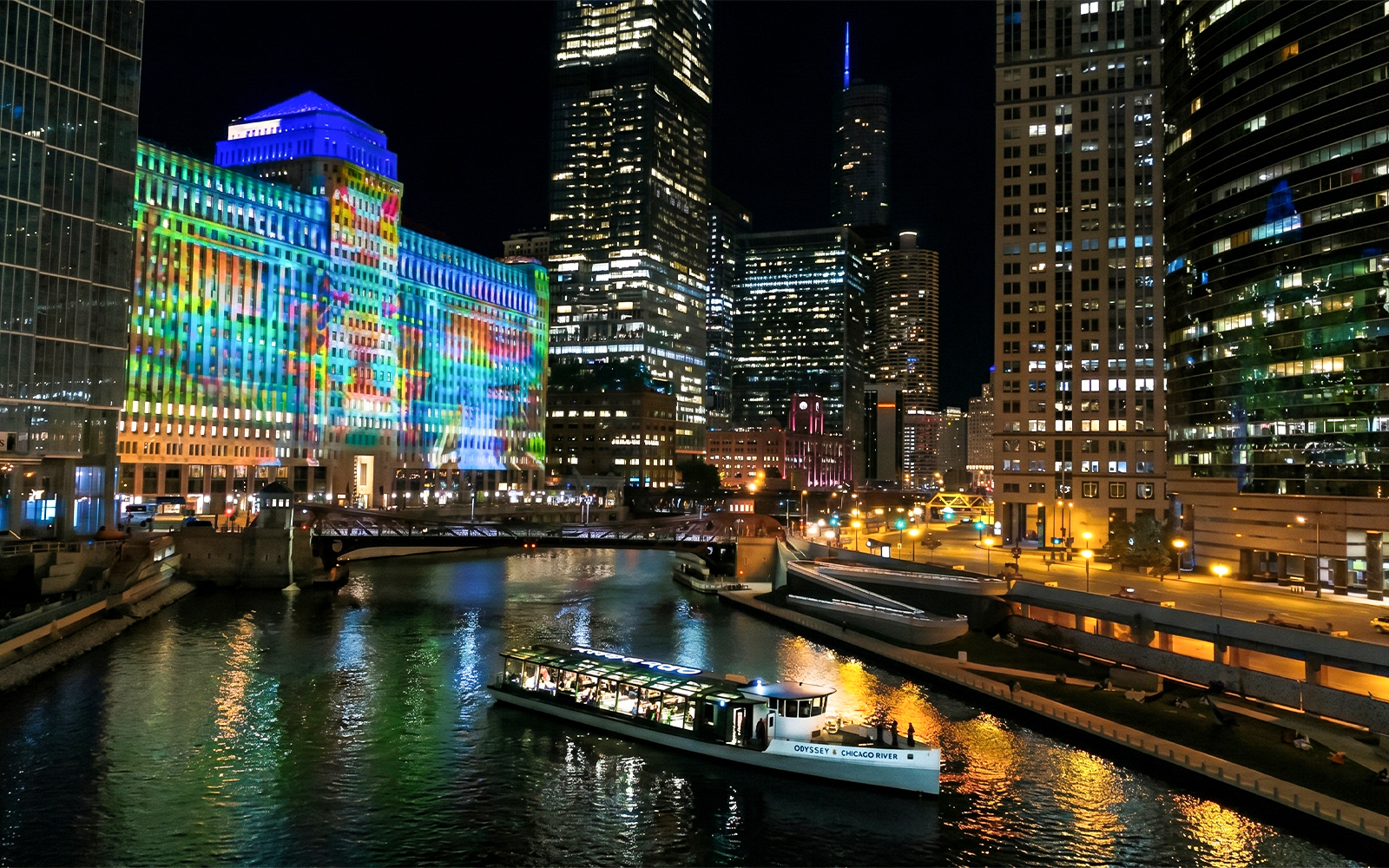 Chicago River dinner cruise with city skyline and colorful building lights.