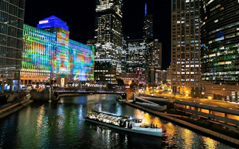 Chicago River dinner cruise with city skyline and colorful building lights.