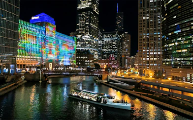 Chicago River dinner cruise with city skyline and colorful building lights.