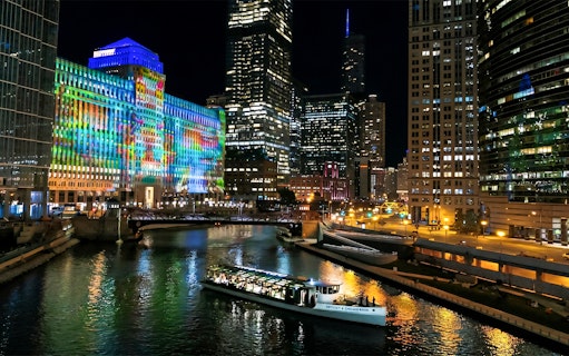 Chicago River dinner cruise with city skyline and colorful building lights.