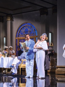 Actors performing a musical scene in a Vienna theater with elegant costumes and set design.