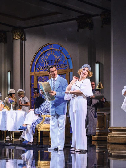 Actors performing a musical scene in a Vienna theater with elegant costumes and set design.
