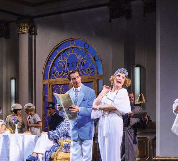 Actors performing a musical scene in a Vienna theater with elegant costumes and set design.