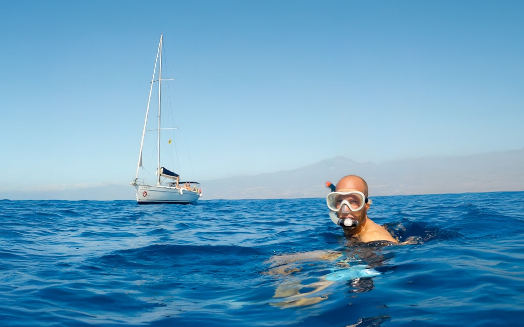 Snorkeler in ocean near sailboat during Whale & Dolphin Watching Cruise, Tenerife.