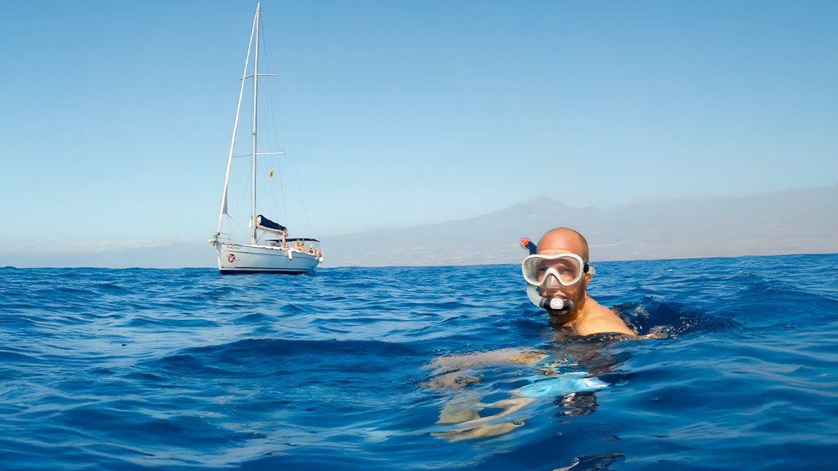 Snorkeler in ocean near sailboat during Whale & Dolphin Watching Cruise, Tenerife.
