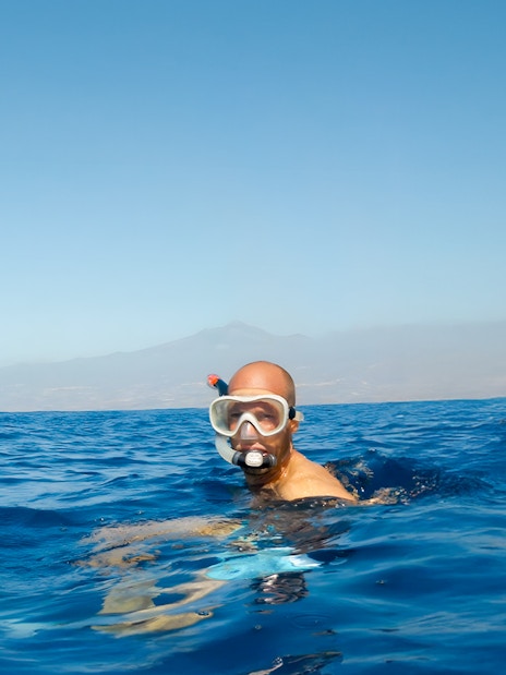 Snorkeler in ocean near sailboat during Whale & Dolphin Watching Cruise, Tenerife.