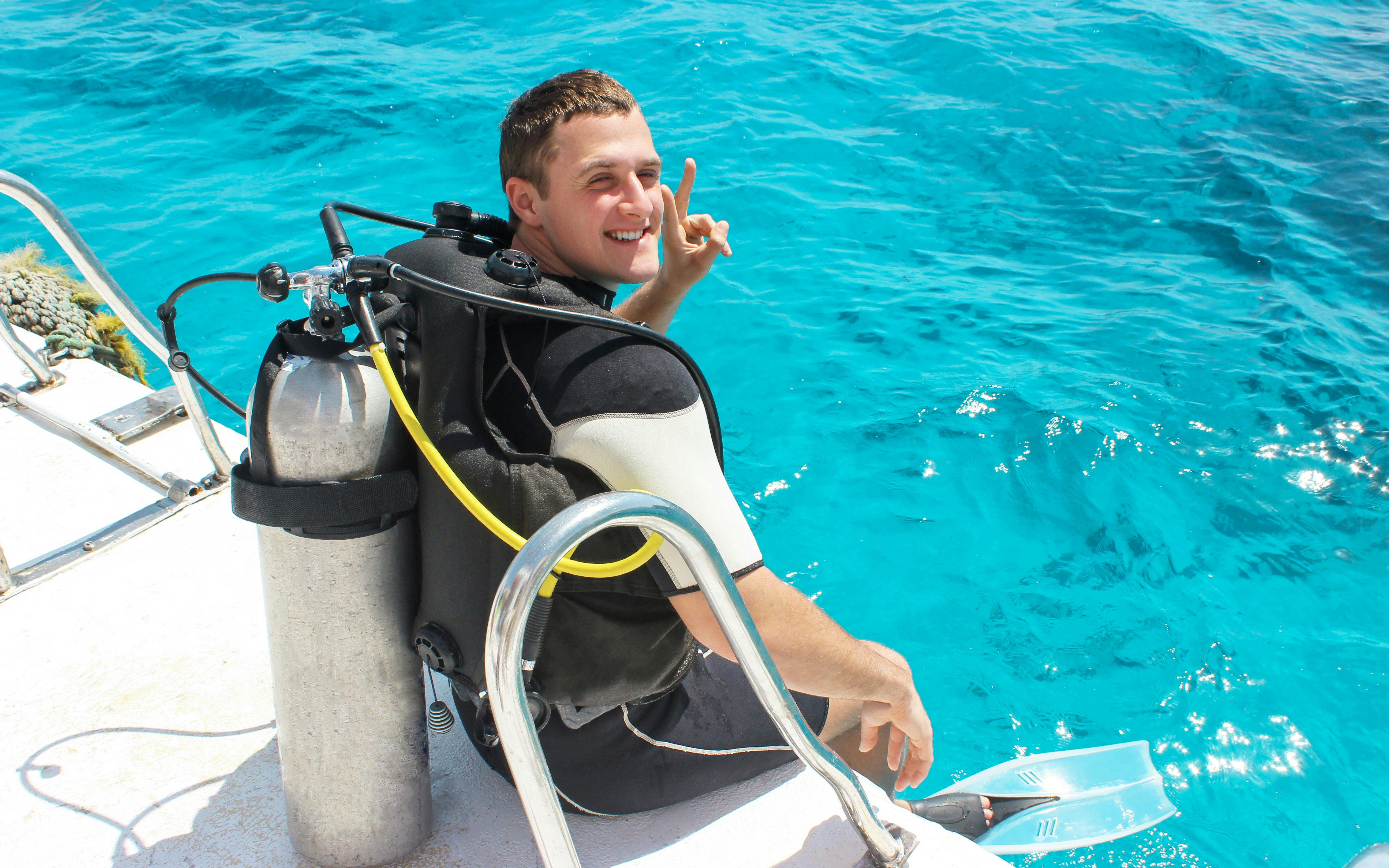 Diver on boat preparing to enter clear ocean water.