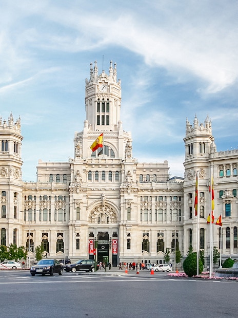 Cibeles Palace in Madrid, view from the street with cars and fountain, part of the Hop-On Hop-Off Bus Tour.