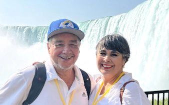 Couple smiling in front of Niagara Falls on adventure tour.
