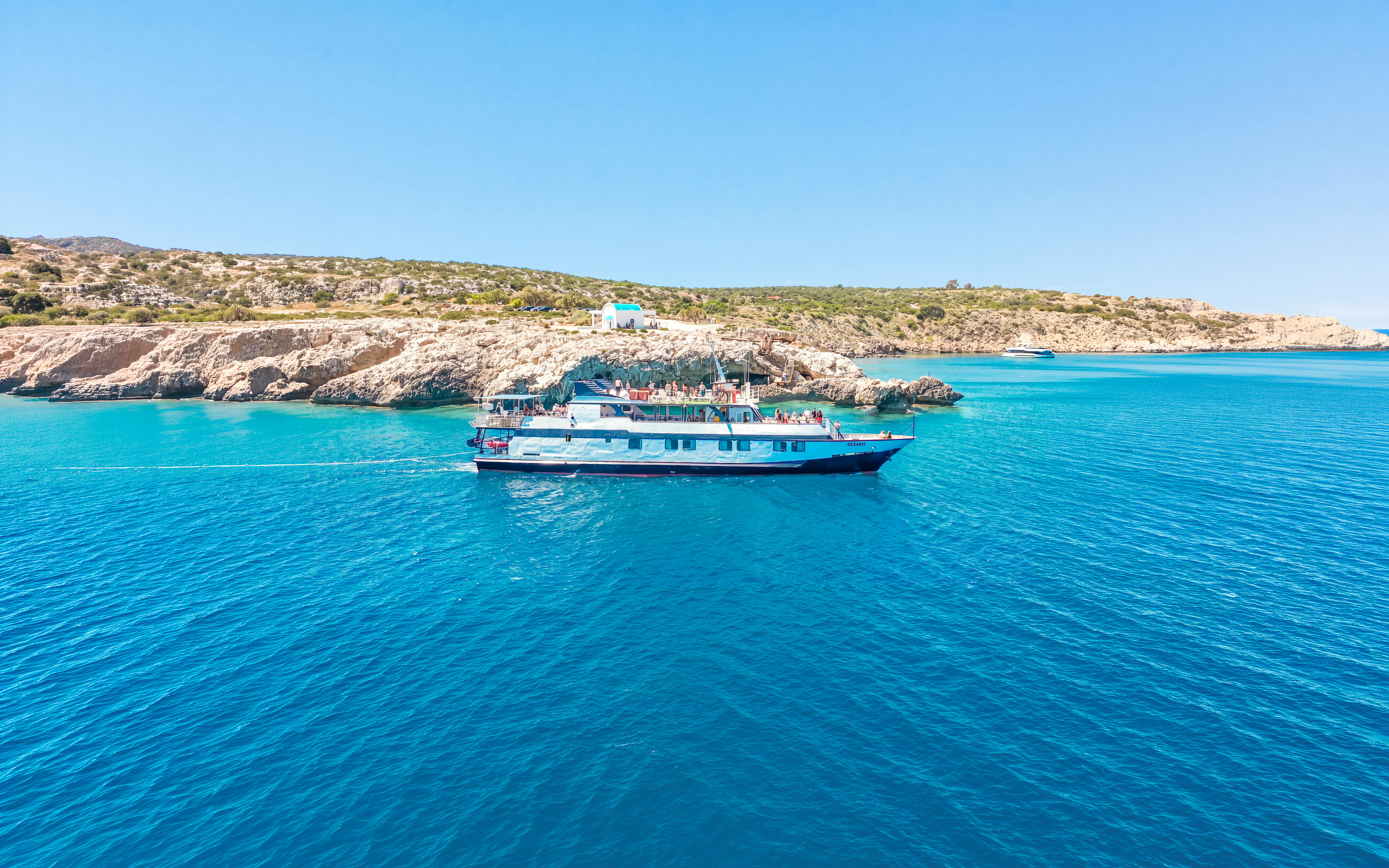 Cruise ship sailing near rocky coastline on Blue Lagoon tour from Larnaca.