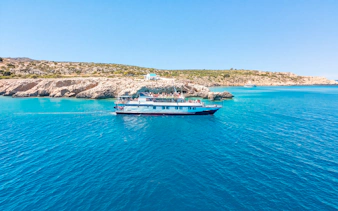 Cruise ship sailing near rocky coastline on Blue Lagoon tour from Larnaca.