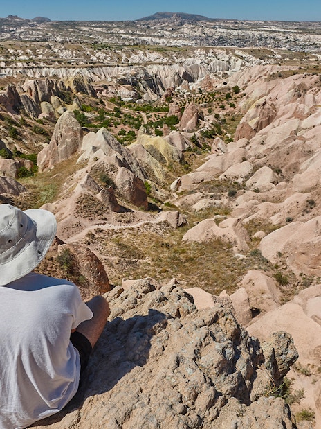 Person sitting on a rock overlooking the unique rock formations at Goreme Open Air Museum, Cappadocia.