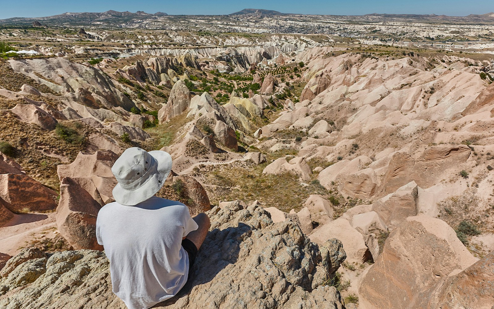 Person sitting on a rock overlooking the unique rock formations at Goreme Open Air Museum, Cappadocia.