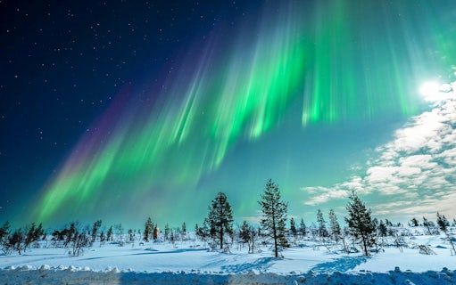 Northern Lights over snowy landscape on Tromso chase tour, Norway.