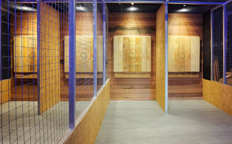 Axe throwing lanes with wooden targets at Axe Factor indoor facility.