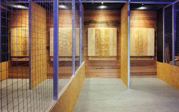 Axe throwing lanes with wooden targets at Axe Factor indoor facility.