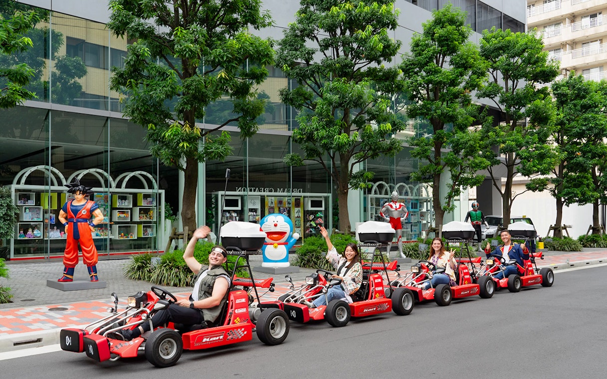 People enjoying Akihabara GoKart Experience in Tokyo, driving past anime statues.