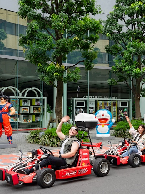 People enjoying Akihabara GoKart Experience in Tokyo, driving past anime statues.