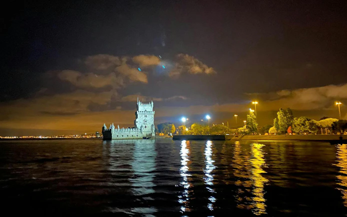 Belem Tower illuminated at night during a Lisbon cruise.