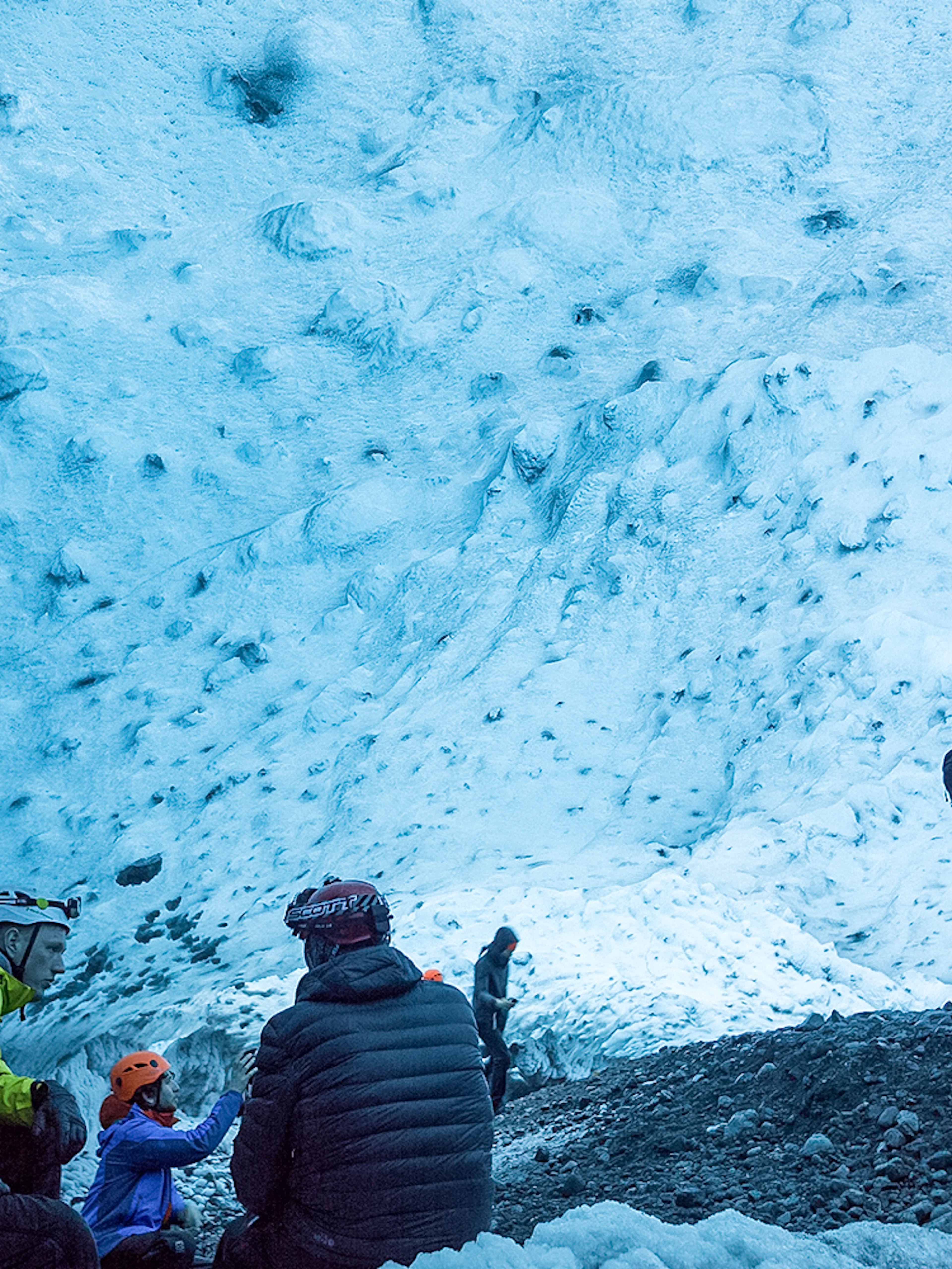 Visitors exploring the blue ice walls of a crystal ice cave in Iceland.