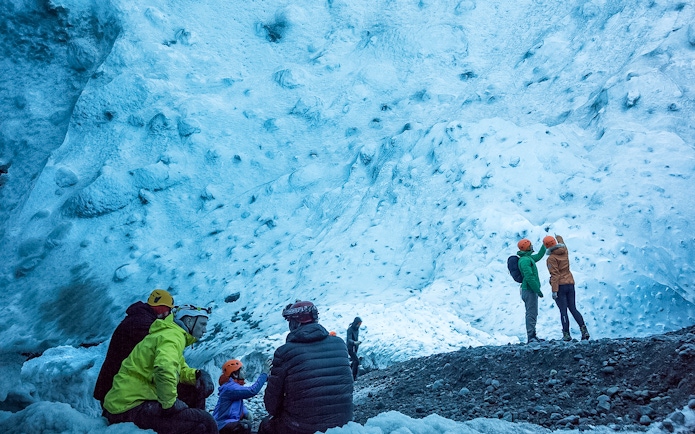 Visitors exploring the blue ice walls of a crystal ice cave in Iceland.