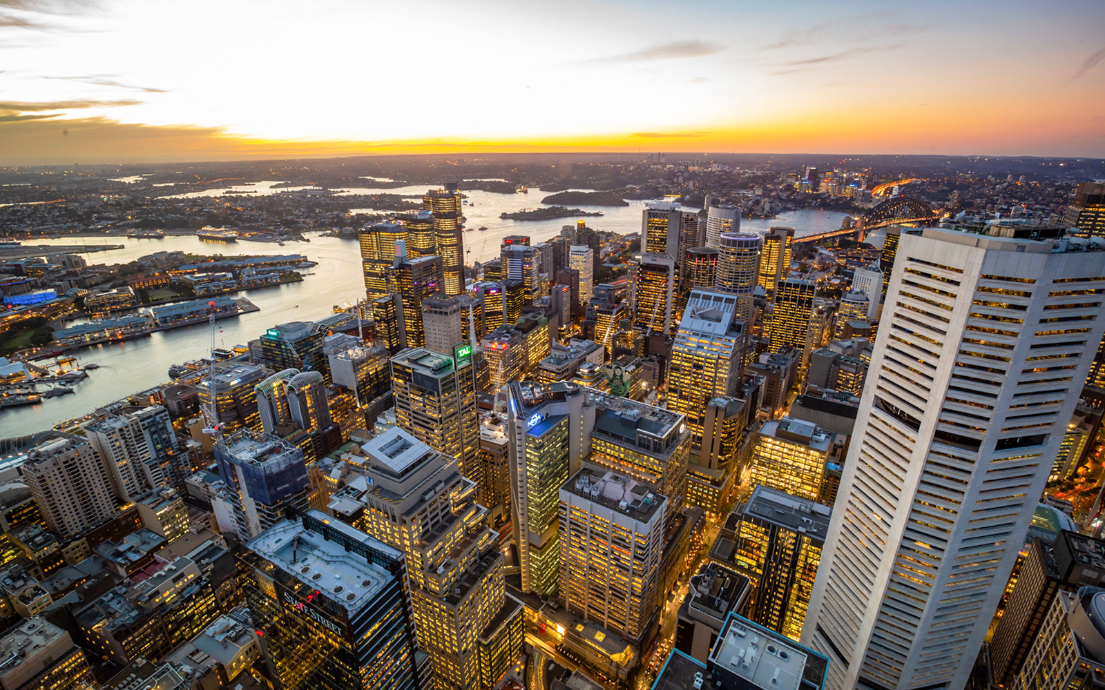 Aerial view of Sydney skyline at sunset with Sydney Harbour in the background.