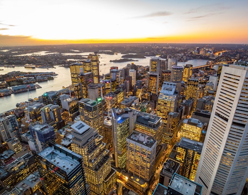 Aerial view of Sydney skyline at sunset with Sydney Harbour in the background.